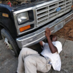 Mr. Green Thumb Under Truck with Hand on Bumper